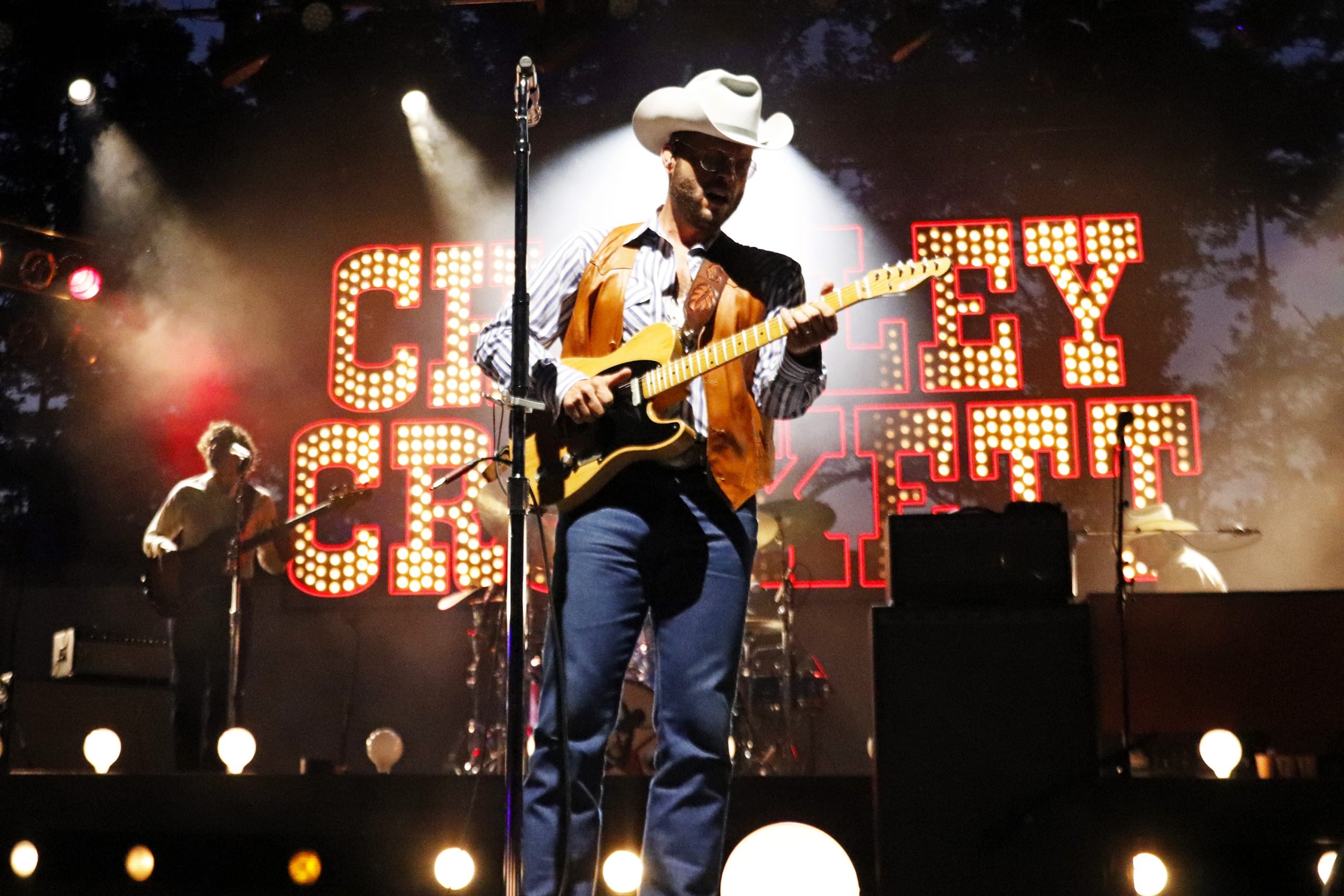 Charley Crockett stands with his guitar on stage.