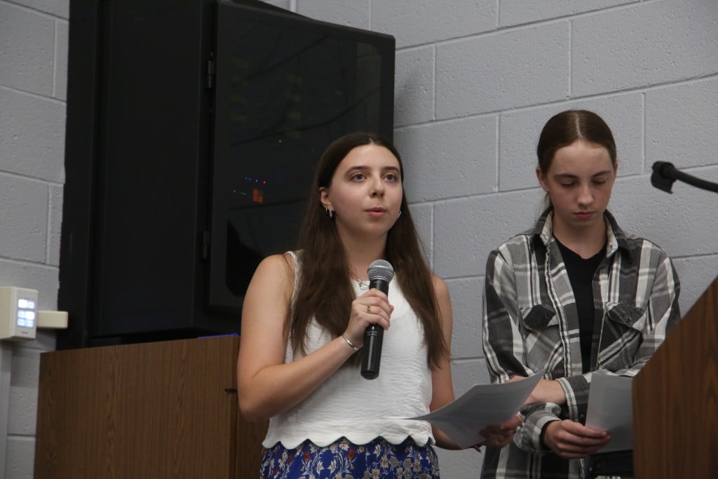 Person holding a microphone and a piece of paper.