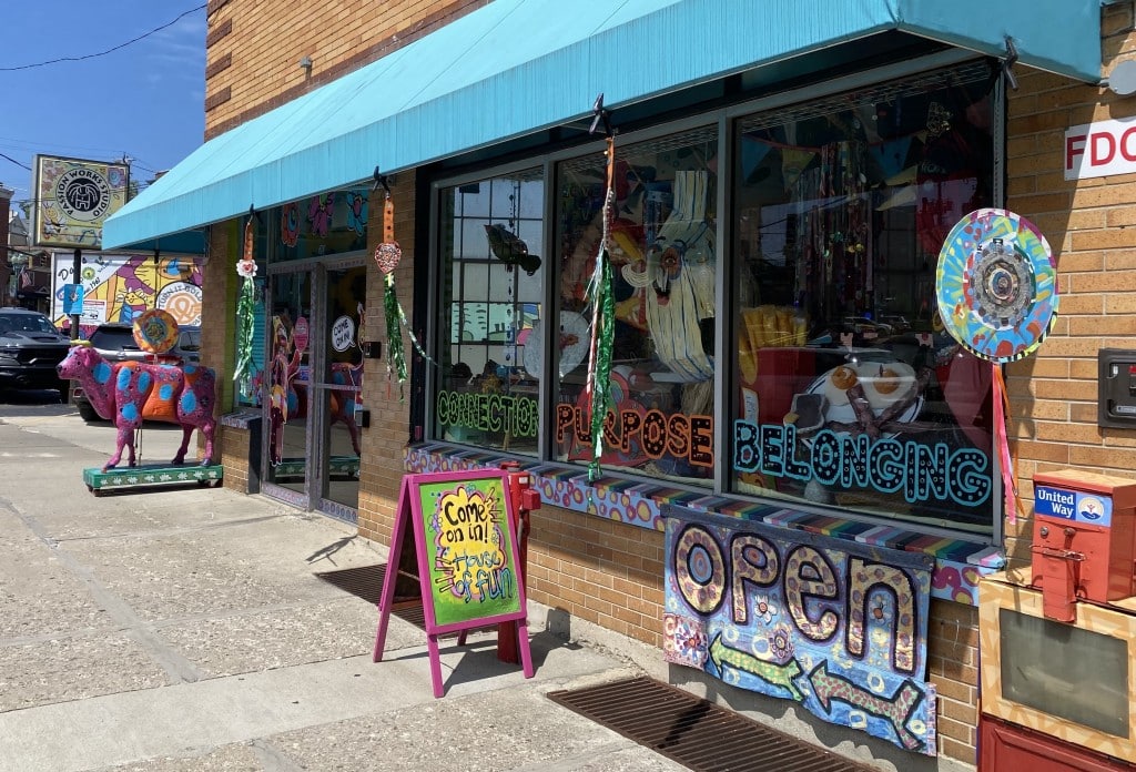 The hanging circular artworks and distinctive lettering in the windows of the Passion Works storefront mirror banners Passion Works Executive Director Patty Mitchell has made for the Athens County Democratic Party over the years. Photo by Dani Kington.