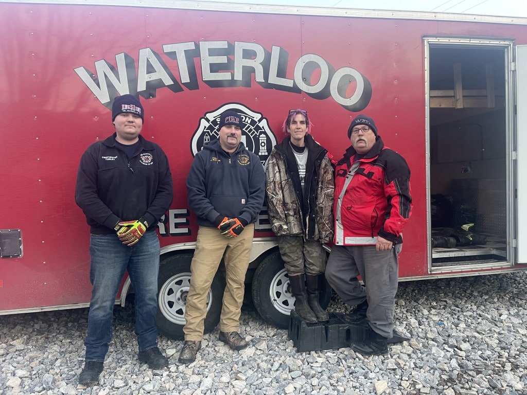 Four people standing in front of a Waterloo Fire Department truck.