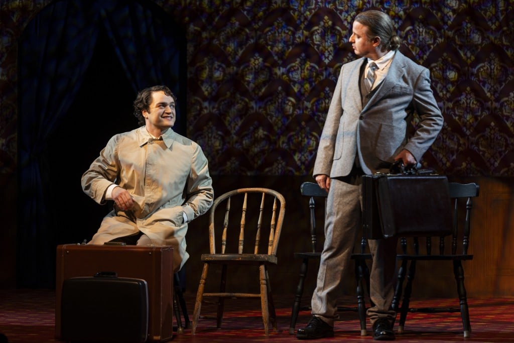 Two characters in Cabaret having a conversation, one sitting in a chair