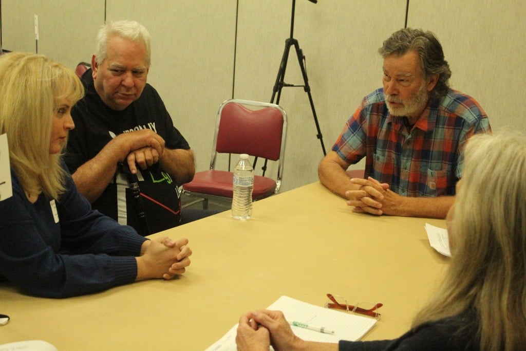 Four people sit around a table in conversation.